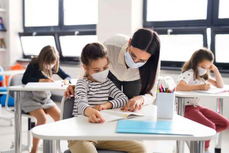 Teacher And Children With Face Mask Back At School